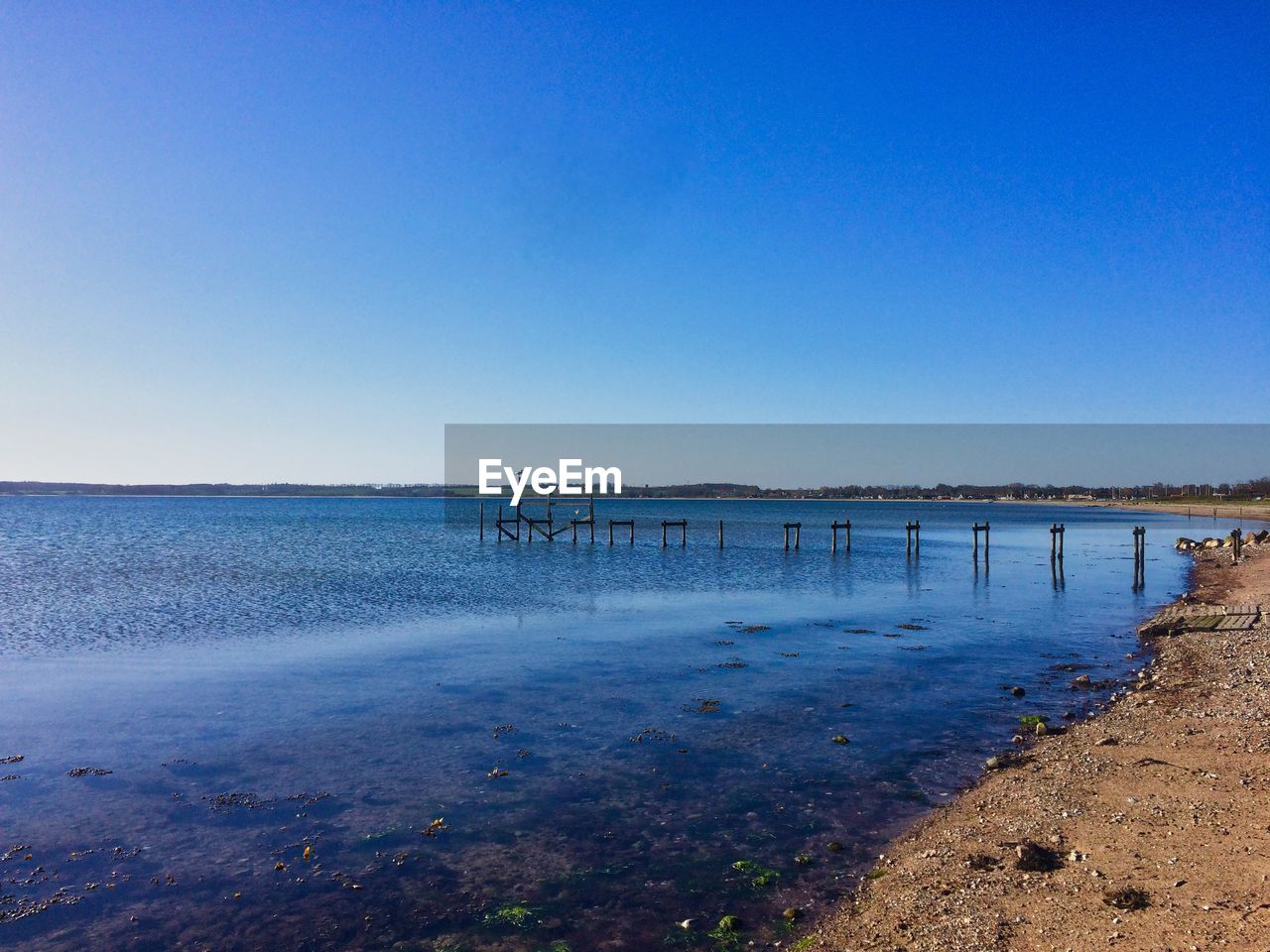 Scenic view of beach against clear blue sky