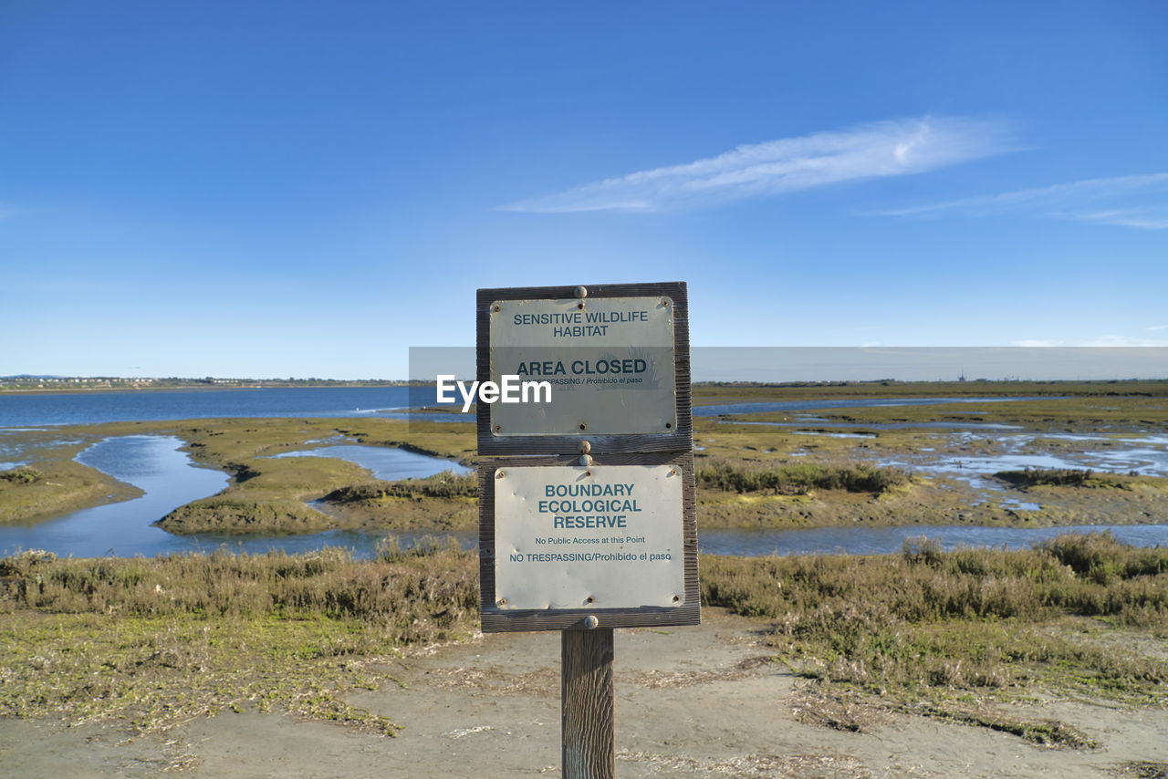 WARNING SIGN ON FIELD AGAINST SKY