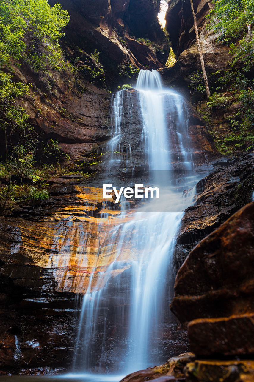 SCENIC VIEW OF WATERFALL AGAINST ROCKS