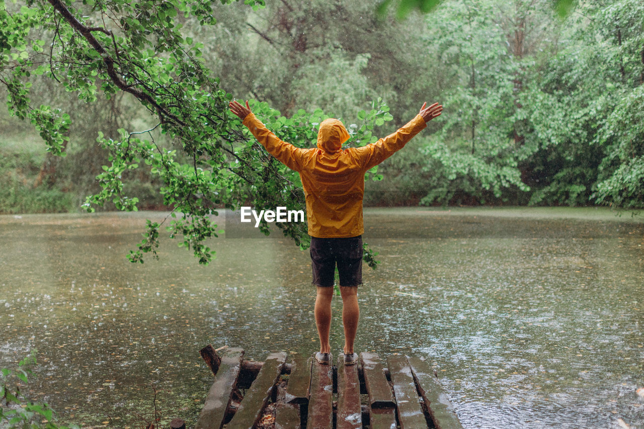 REAR VIEW OF PERSON STANDING IN RAIN