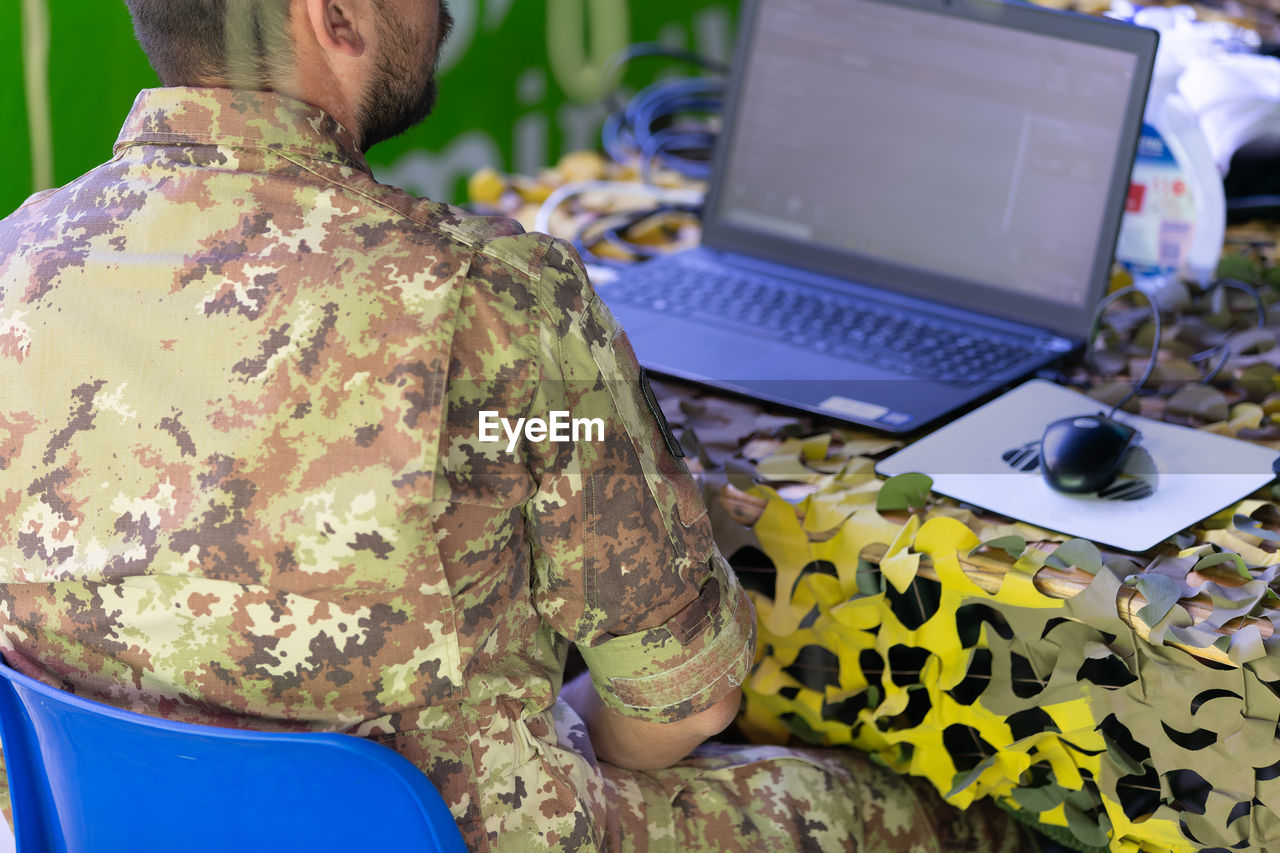 laptop, computer, technology, adult, communication, person, wireless technology, using laptop, army, one person, military, clothing, men, occupation, camouflage clothing, armed forces, sitting, rear view, working, government, soldier, indoors, business, military uniform