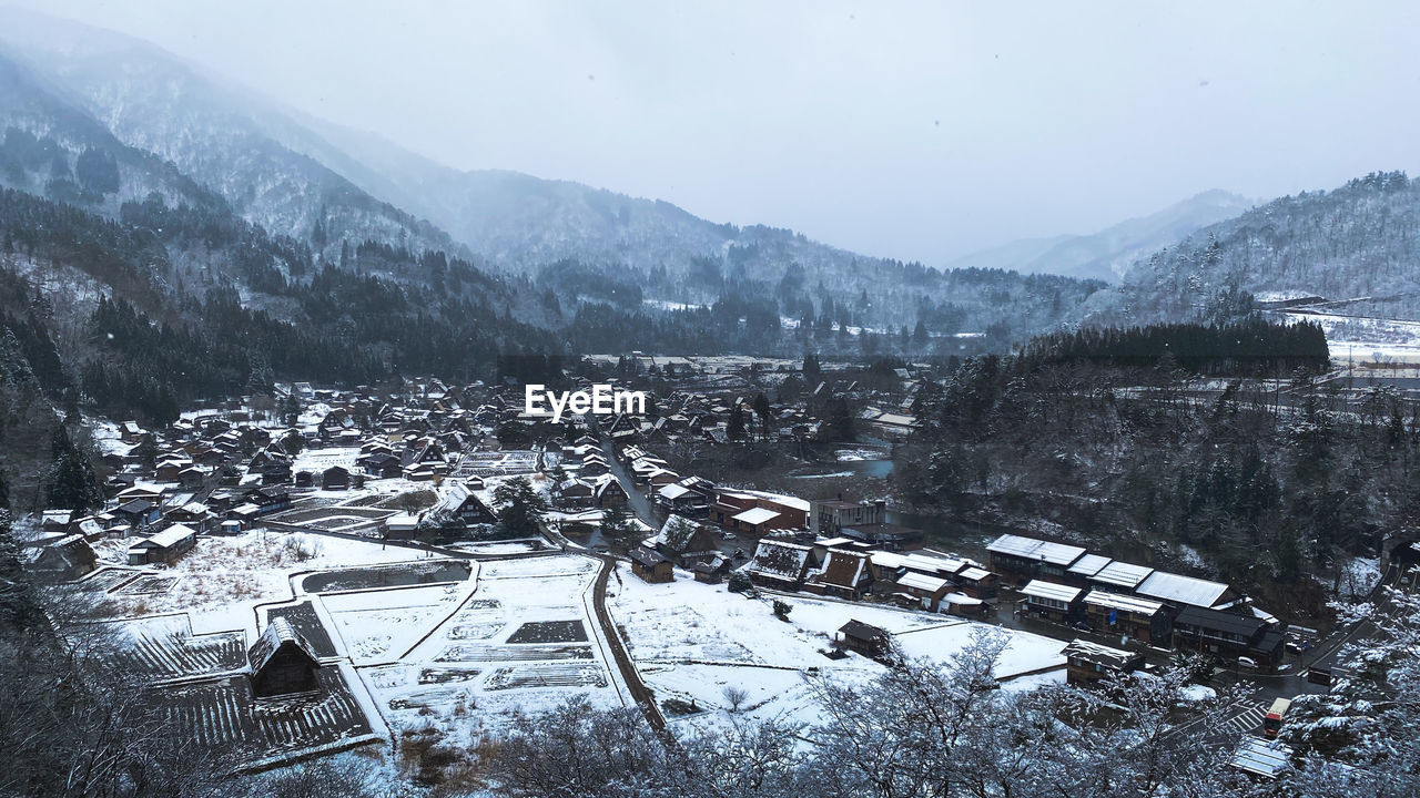 High angle view of buildings and snowcapped mountains against sky