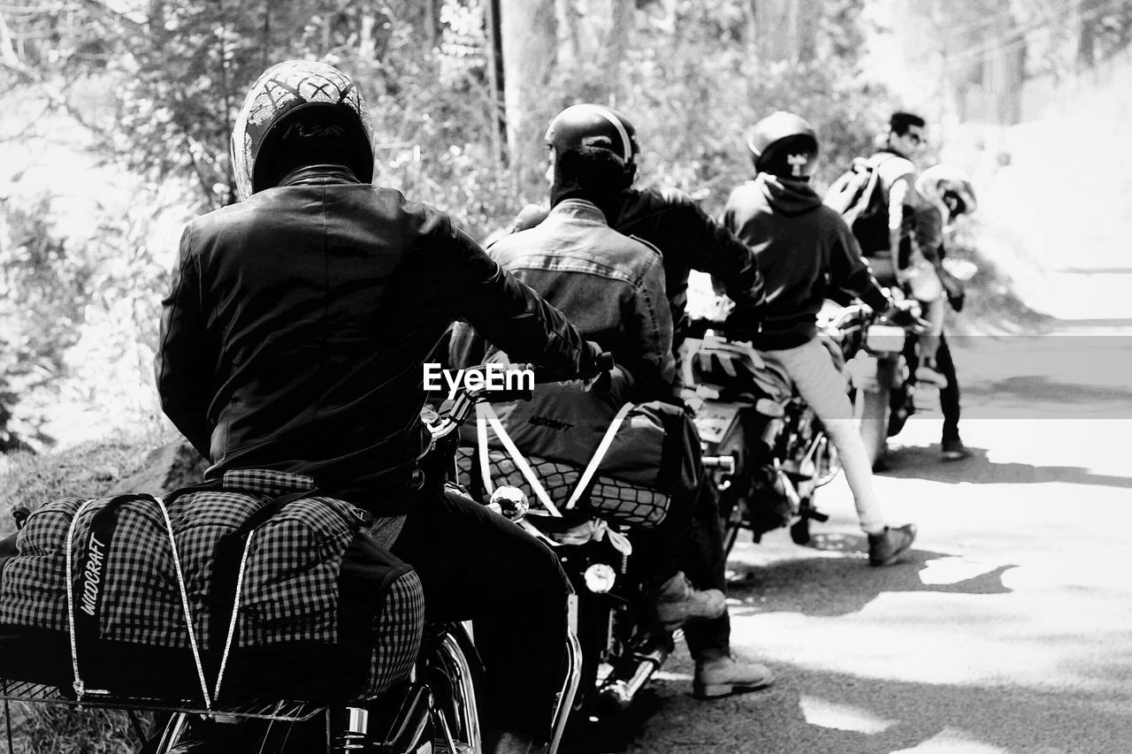 Rear view of men riding motorcycles on road