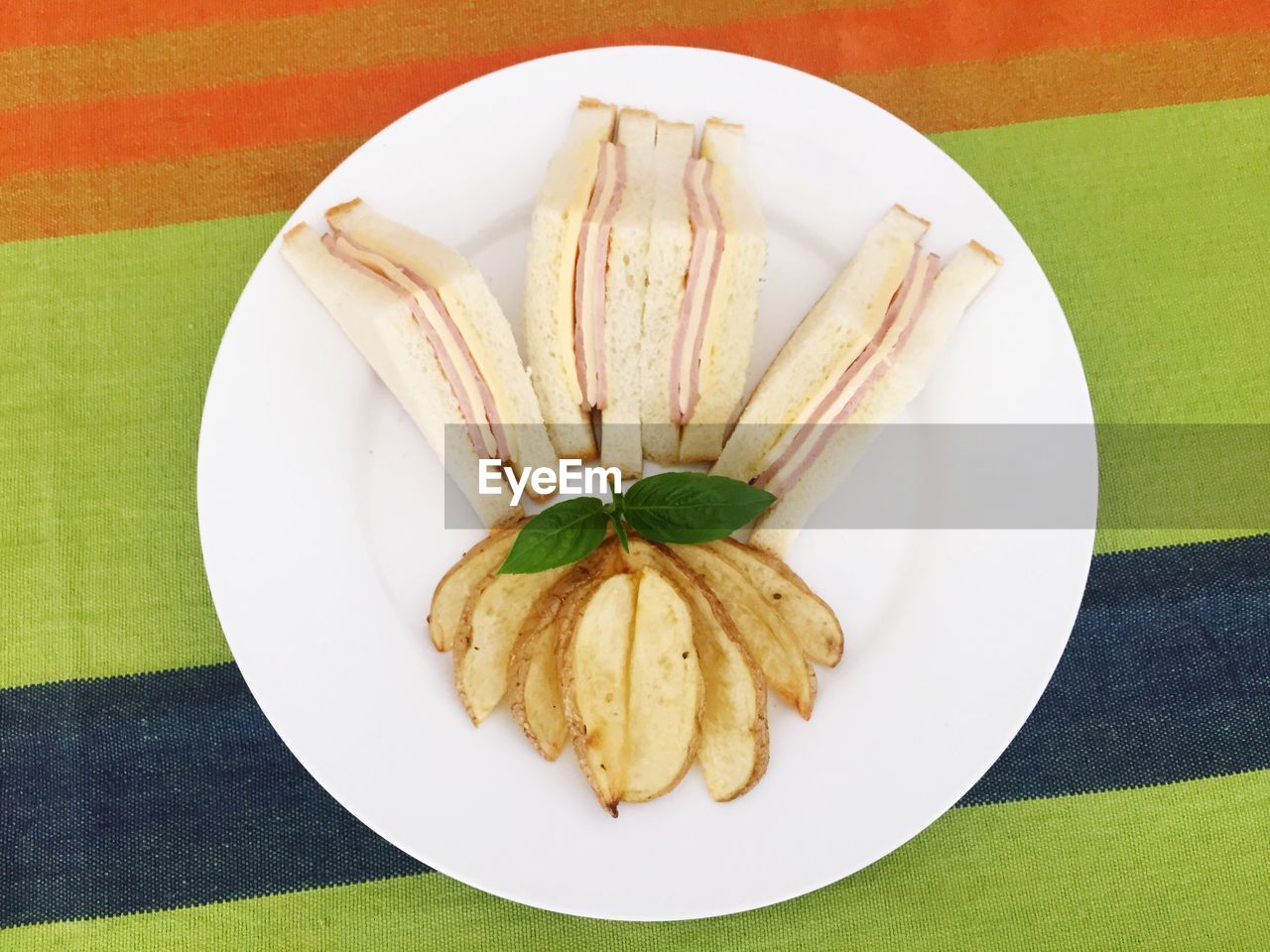 Directly above shot of potato chips and sandwiches in plate on table