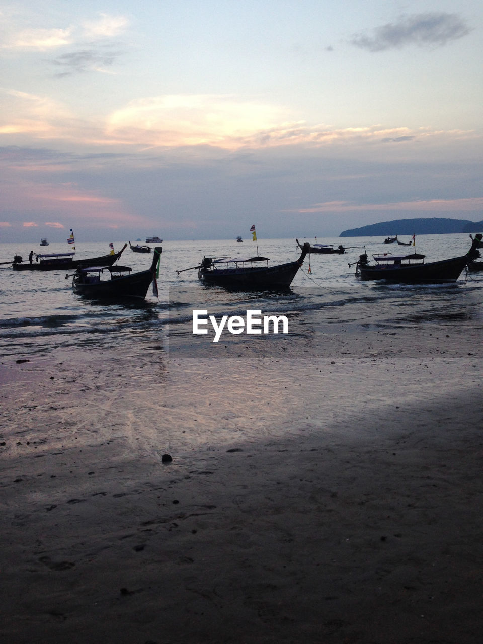 Boats in sea at sunset