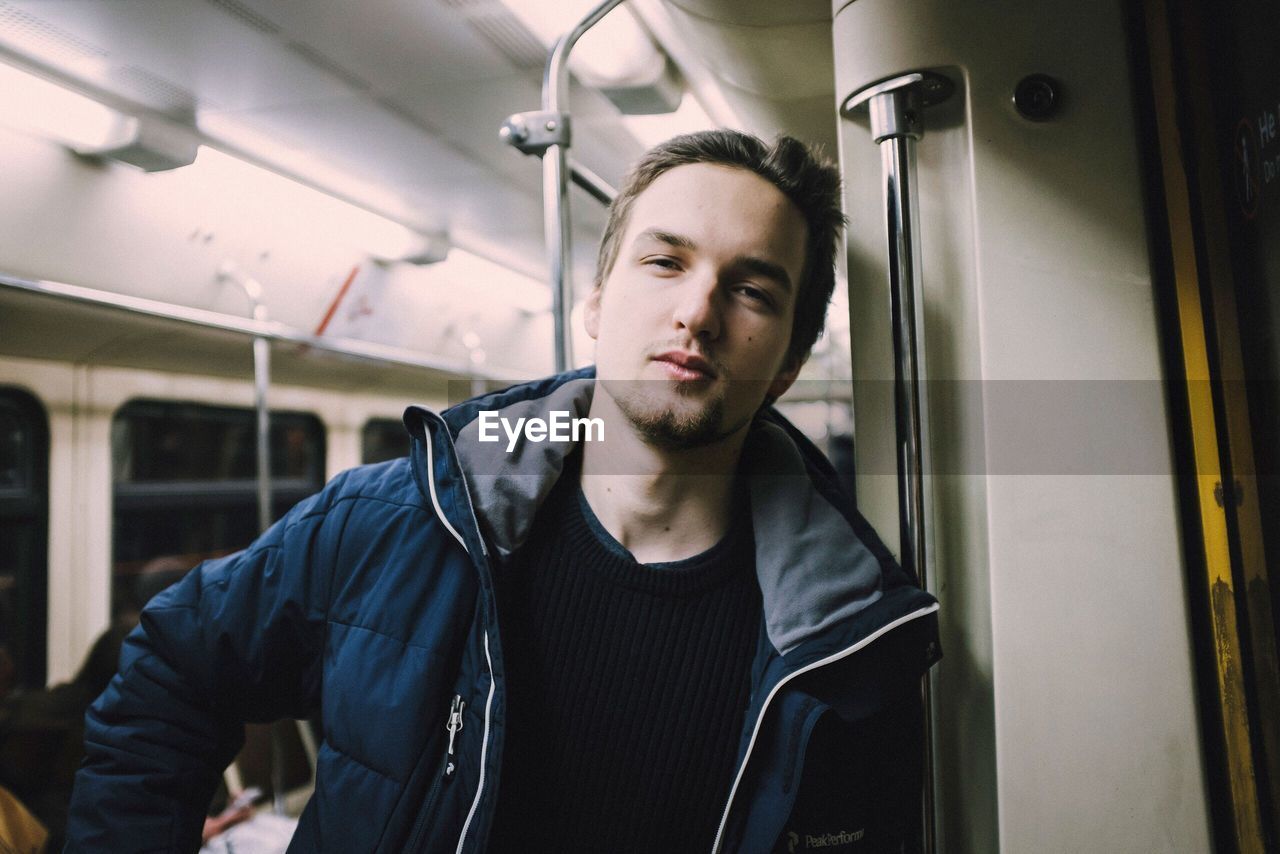 Portrait of handsome young man standing in train