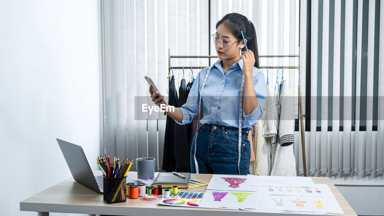 YOUNG WOMAN USING SMART PHONE ON TABLE