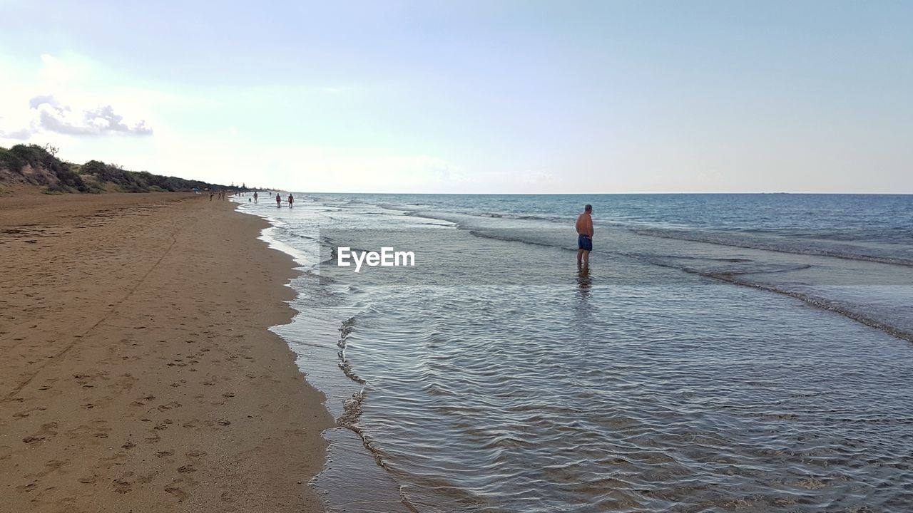 WOMAN ON BEACH AGAINST SKY