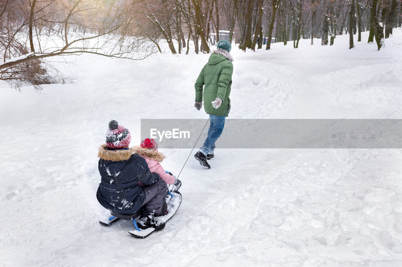 winter, cold temperature, snow, warm clothing, child, childhood, full length, clothing, footwear, nature, two people, family, sled, togetherness, men, tree, leisure activity, adult, sports, winter sports, female, women, environment, parent, tobogganing, one parent, holiday, vacation, land, trip, fun, walking, lifestyles, mountain, day, emotion, knit hat, bonding, winter coat, hat, sledding, white, rear view, toddler, outdoors, glove, travel, sports equipment, positive emotion, vehicle, motion, plant, nordic skiing, skiing, activity, enjoyment, frozen, snowshoe, forest, landscape