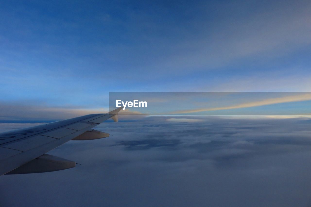 CROPPED IMAGE OF AIRPLANE WING OVER LANDSCAPE