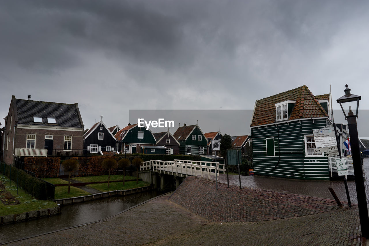 Buildings by houses against sky in city