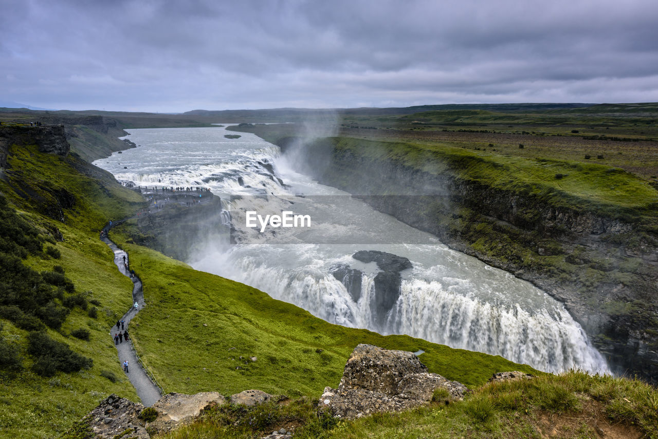 SCENIC VIEW OF WATER FLOWING THROUGH ROCKS AGAINST SKY