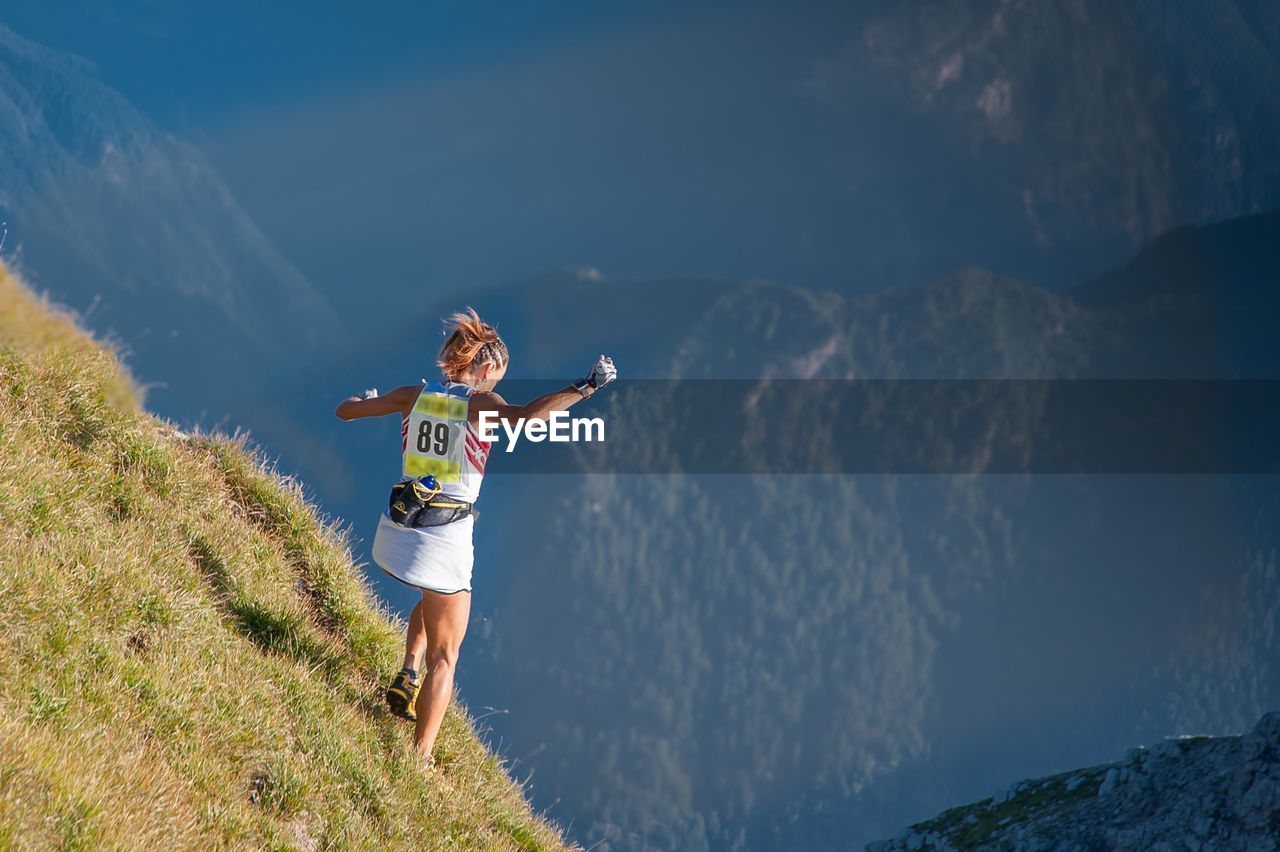 Rear view of man with arms outstretched against mountain range