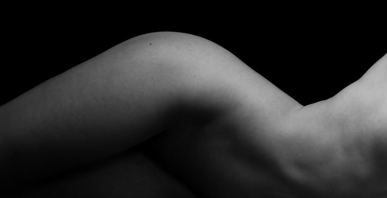Close-up mid section of naked woman over black background