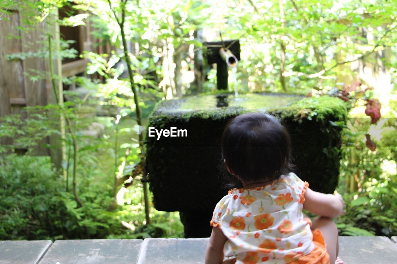 Rear view of baby with fountain in background