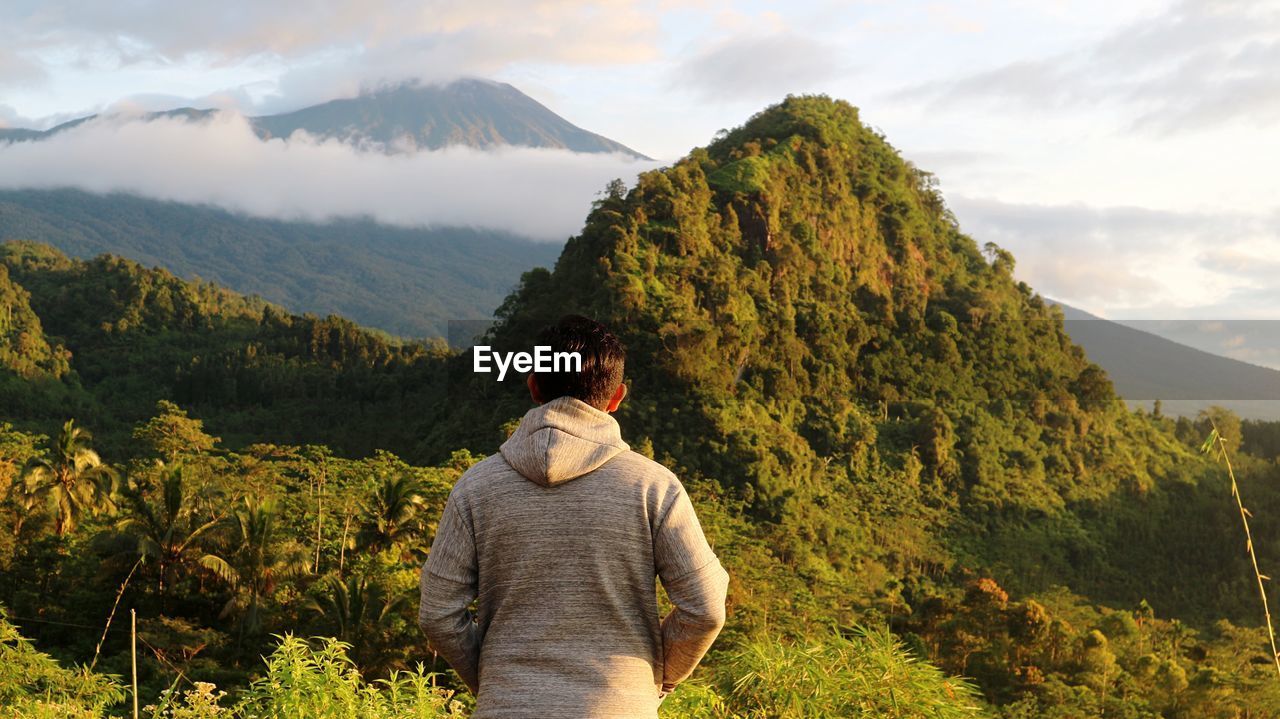 Rear view of man wearing hood while standing against mountain