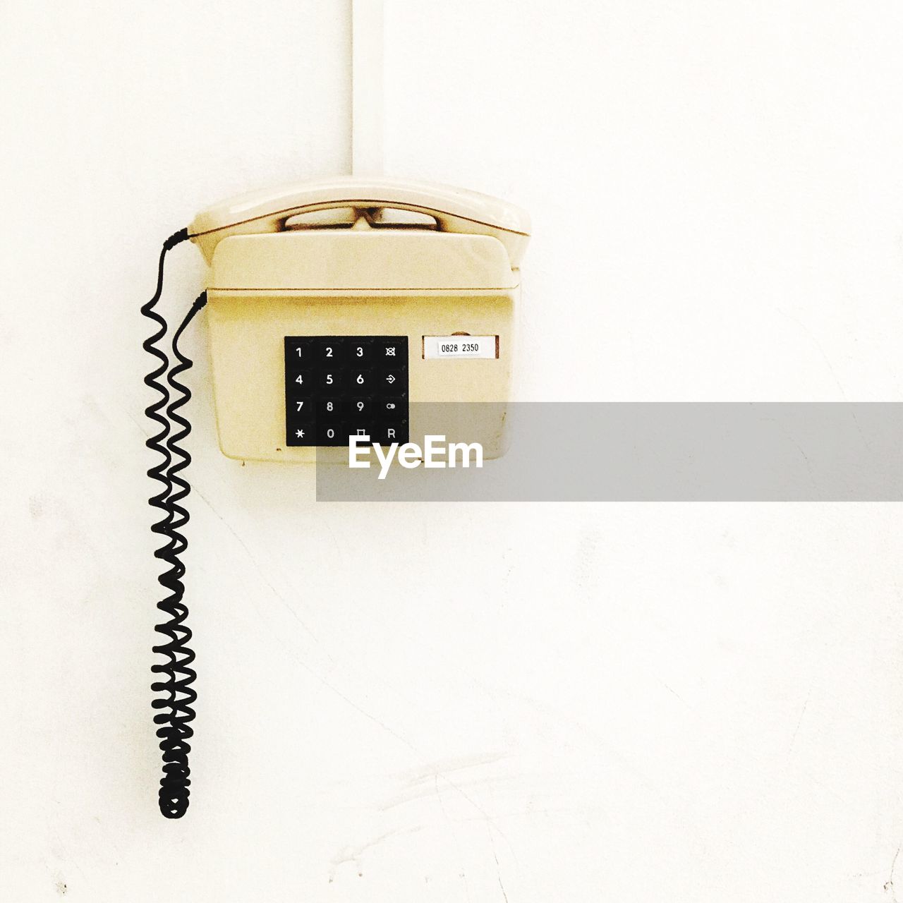 Close-up of telephone booth against white wall