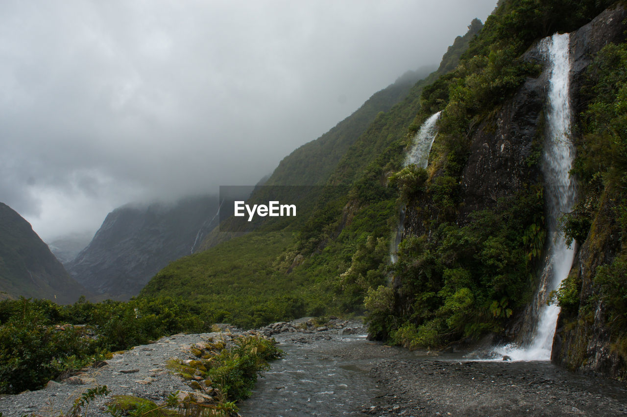 Scenic view of river amidst mountains against sky