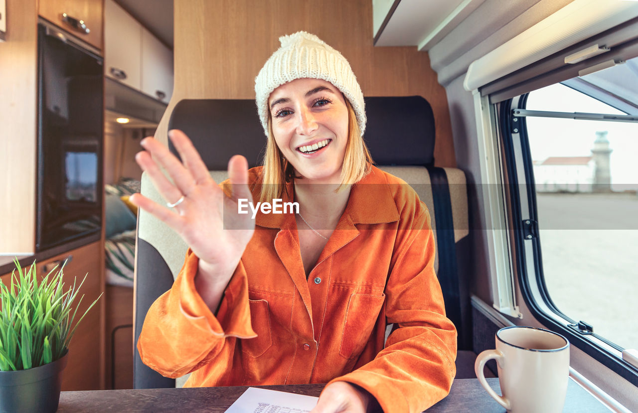 Happy woman waving on video call from her campervan