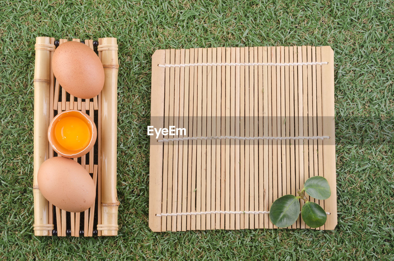 Directly above shot of egg in spoon on bamboo mat over grass