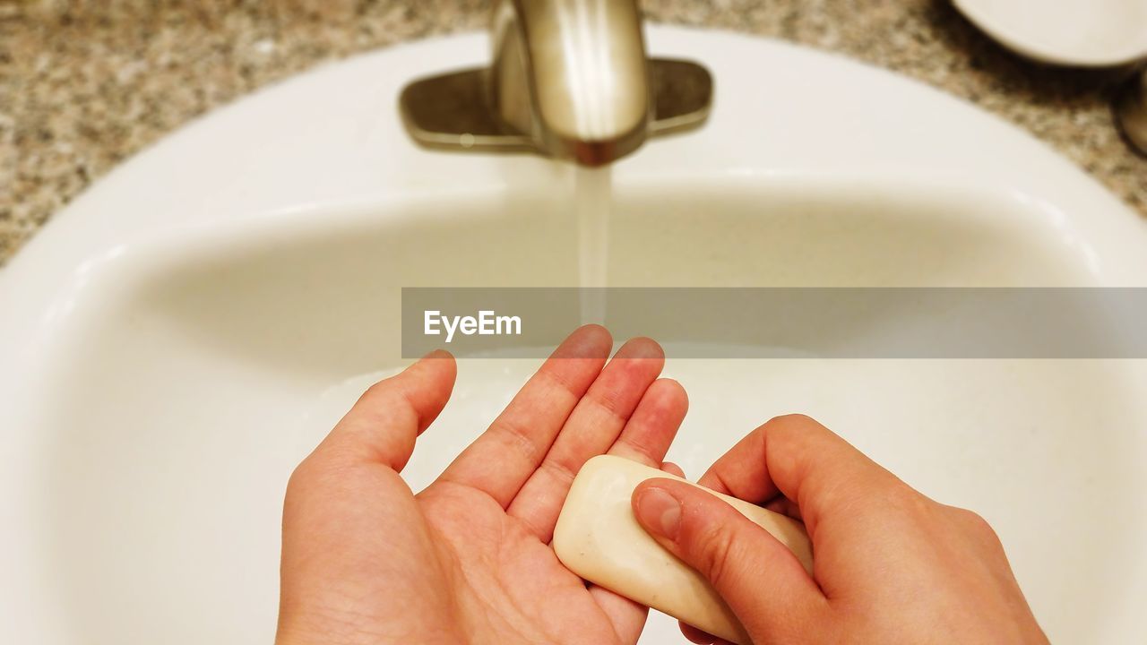 Cropped image of person washing hands at sink
