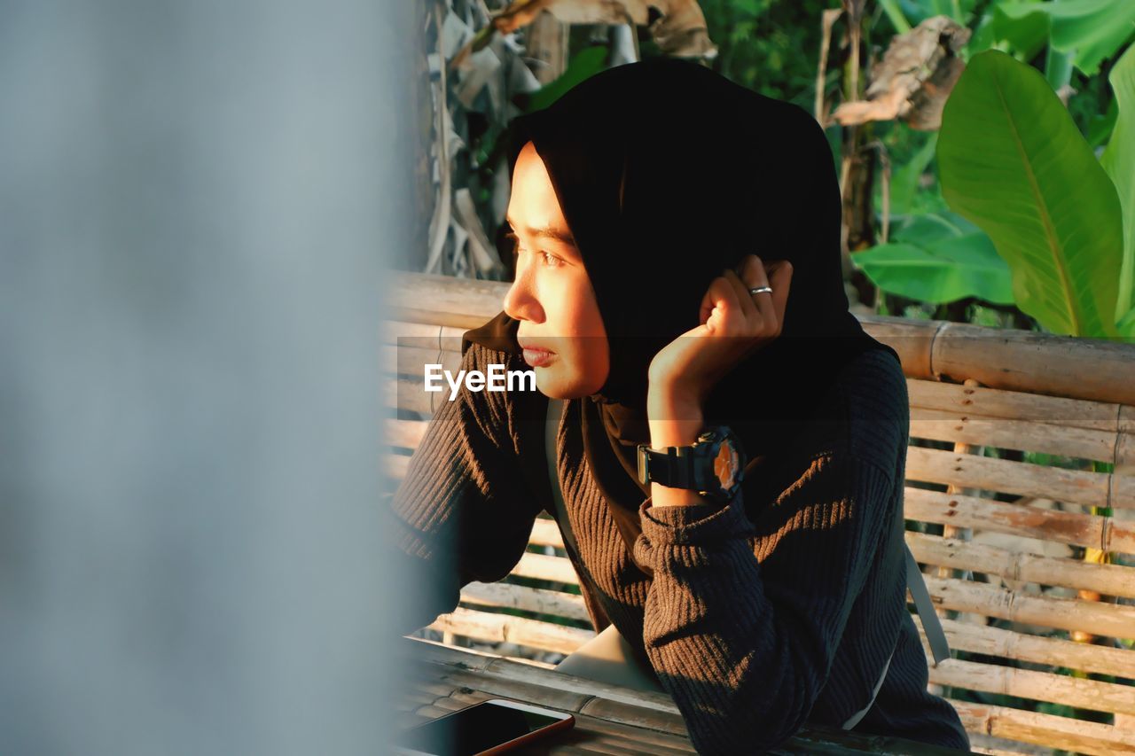 Woman in hijab looking away against plants