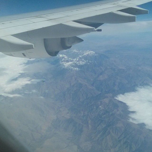 CROPPED IMAGE OF AIRPLANE OVER LANDSCAPE