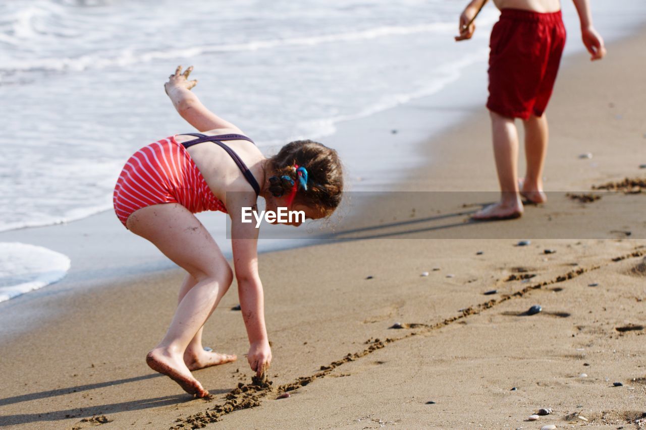 Full length of girl drawing on sand at beach