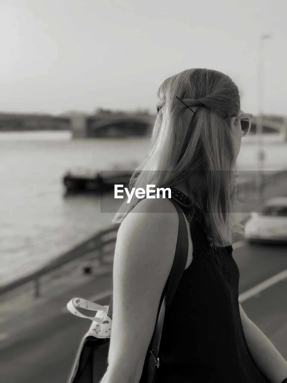 Side view of woman looking away while standing against sky