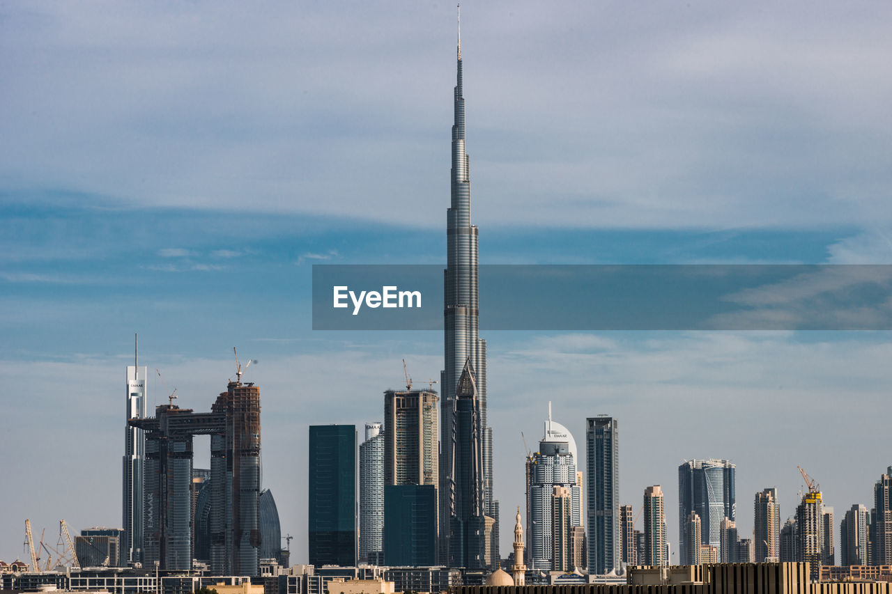 Burj khalifa in city against cloudy sky