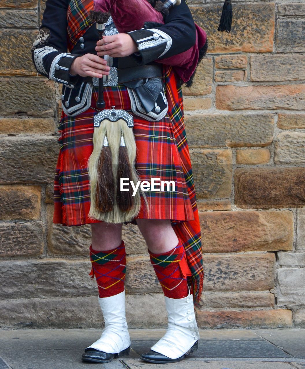 Low section of person in costume standing on footpath against stone wall