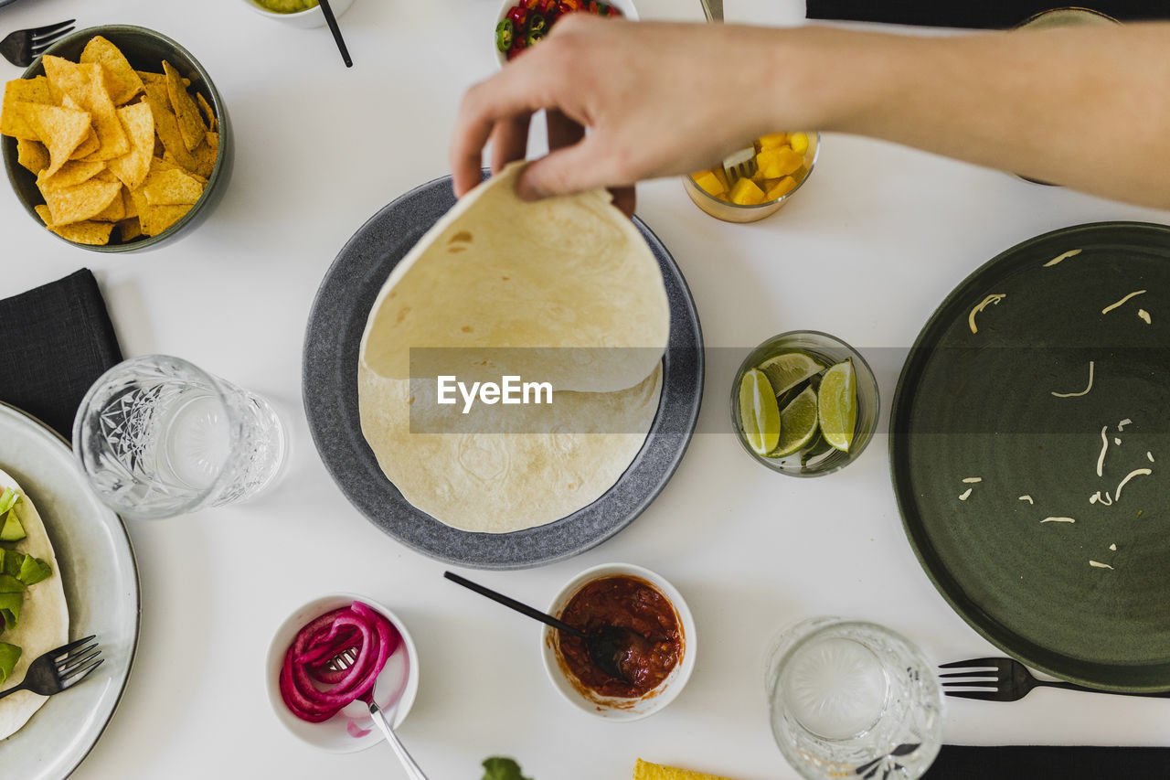 Person taking tortilla from stack during mexican feast