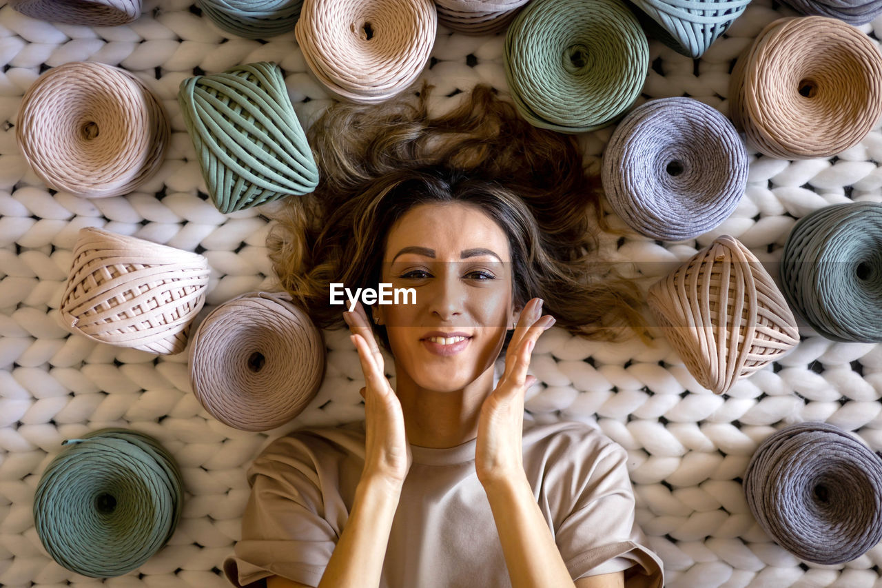 Happy woman amidst multi colored threads