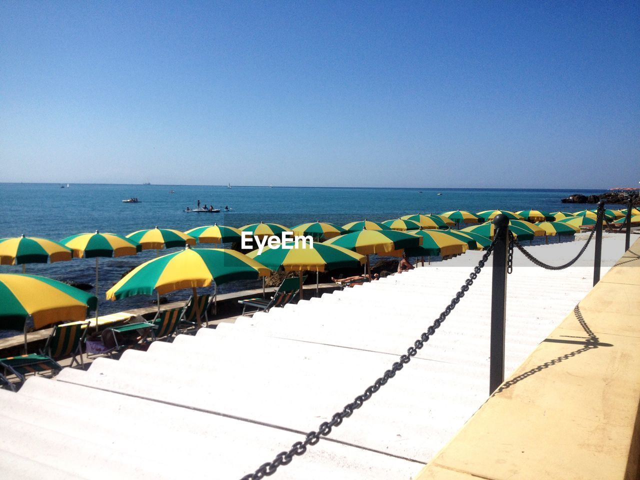 Open parasols by sea against clear sky