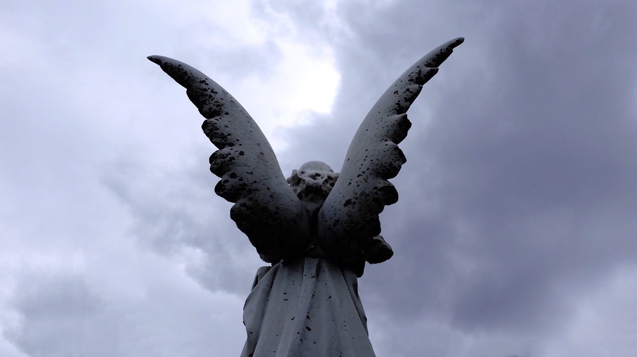 Low angle view of angel statue against cloudy sky
