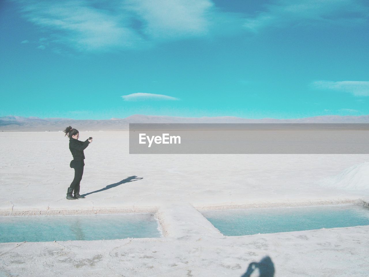 Woman standing on salt pan against sky