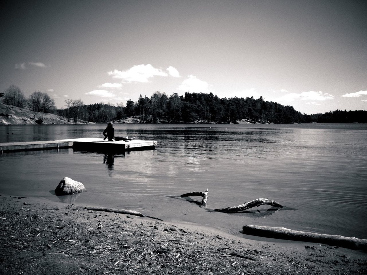 Woman sitting on lake pier