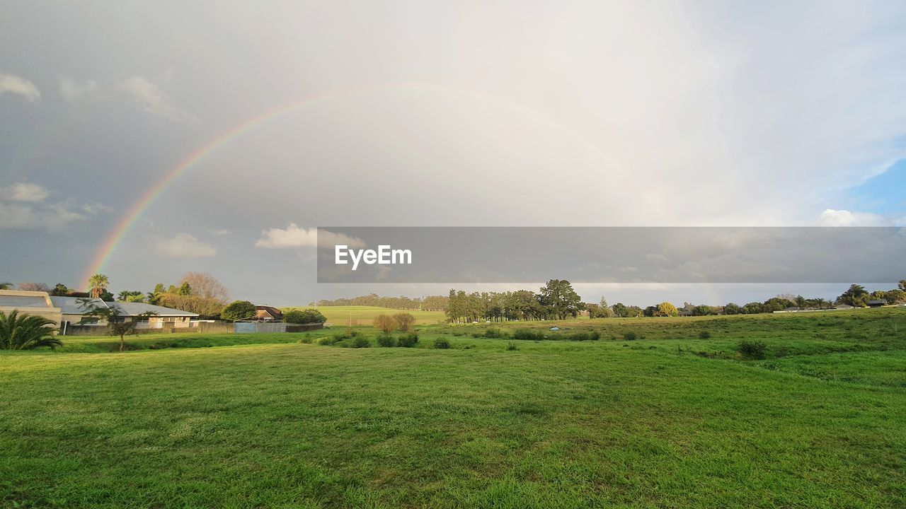 Scenic view of field against rainbow in sky