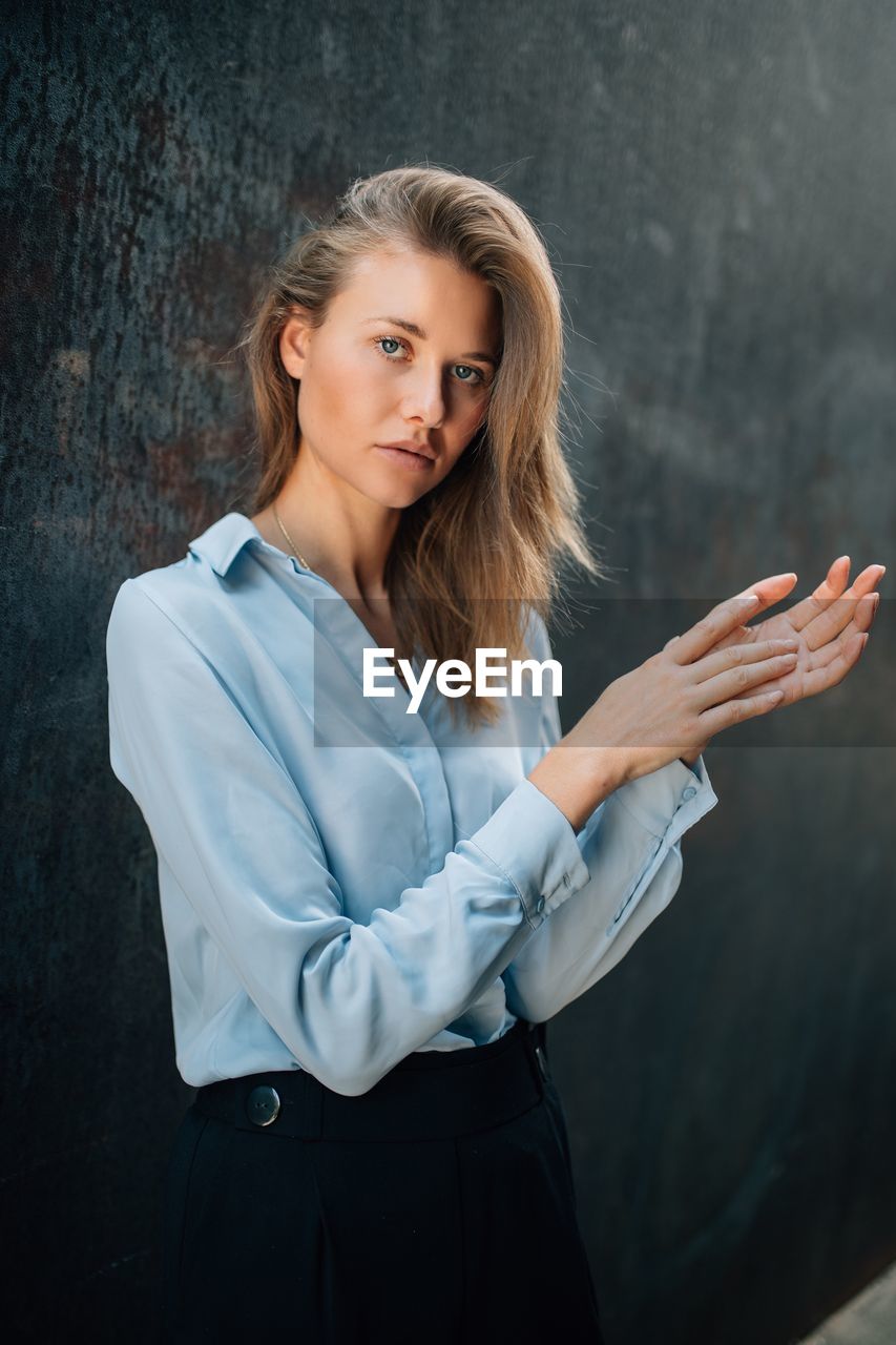 Portrait of young woman standing against wall