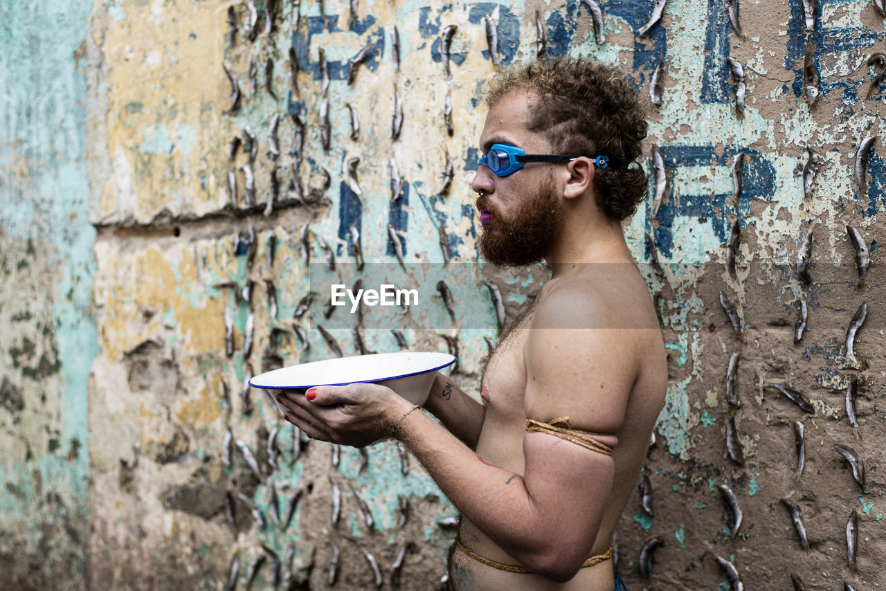 Portrait of young man wearing sunglasses standing against wall