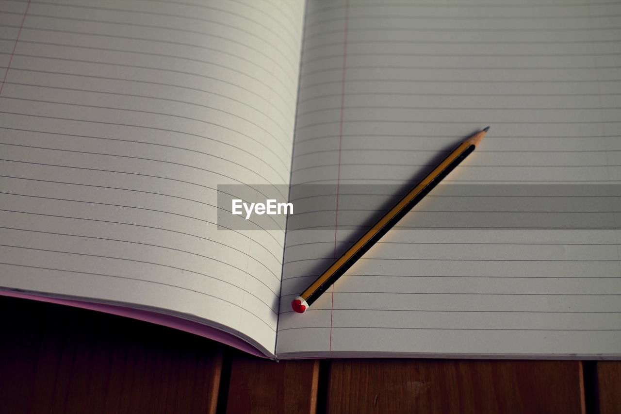 Close-up of book and pencil on wooden table