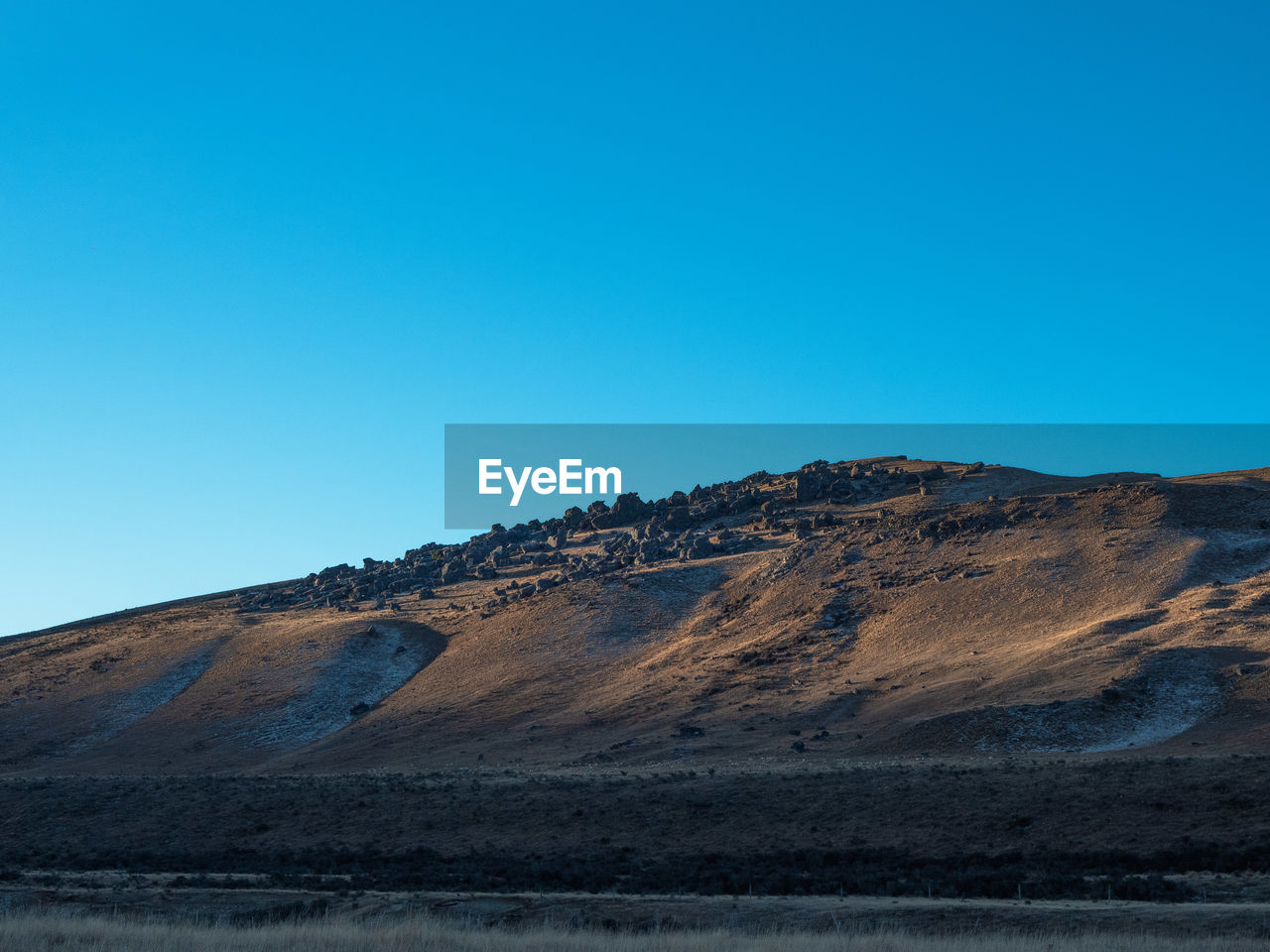 Scenic view of arid landscape against clear blue sky