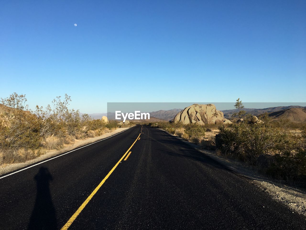 Road leading towards mountain against clear sky