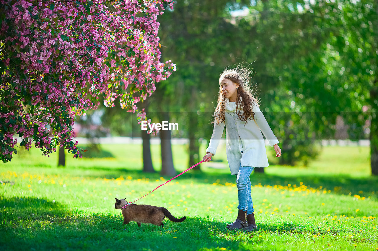 Full length of girl with cat on grass outdoors