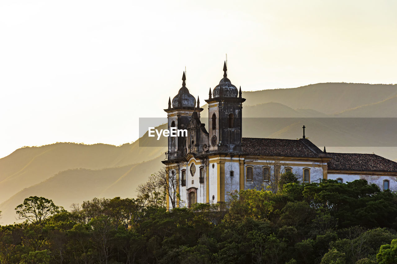 Old church in ouro preto city on top of hill and surrounded by hills during sunset