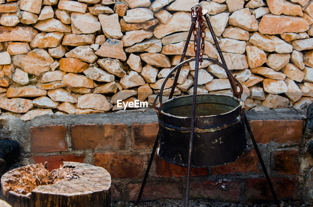 Close-up of fire pit against stone wall at back yard