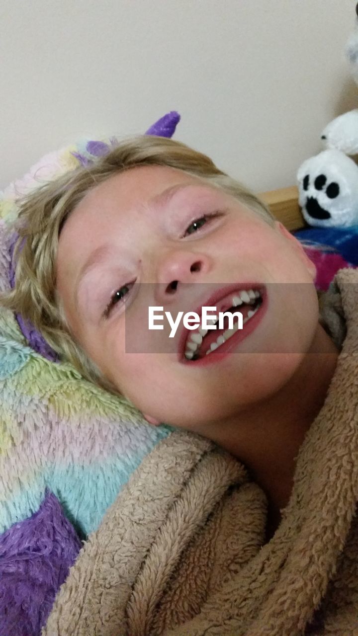 Close-up portrait of happy boy lying on bed