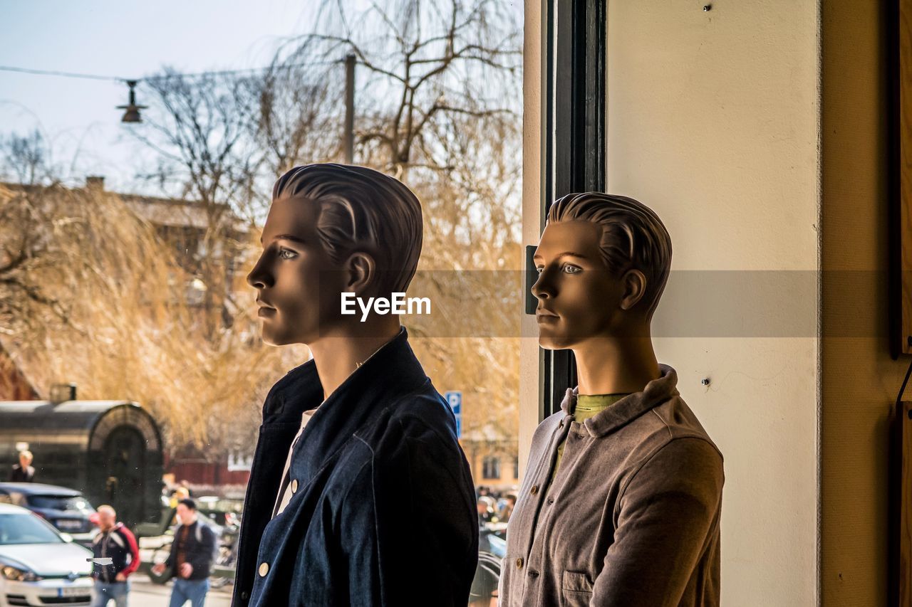  male mannequins looking away against window