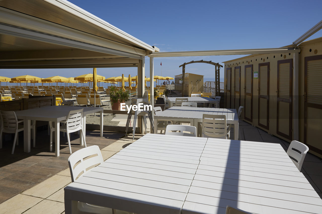 EMPTY TABLES AND CHAIRS AGAINST CLEAR SKY