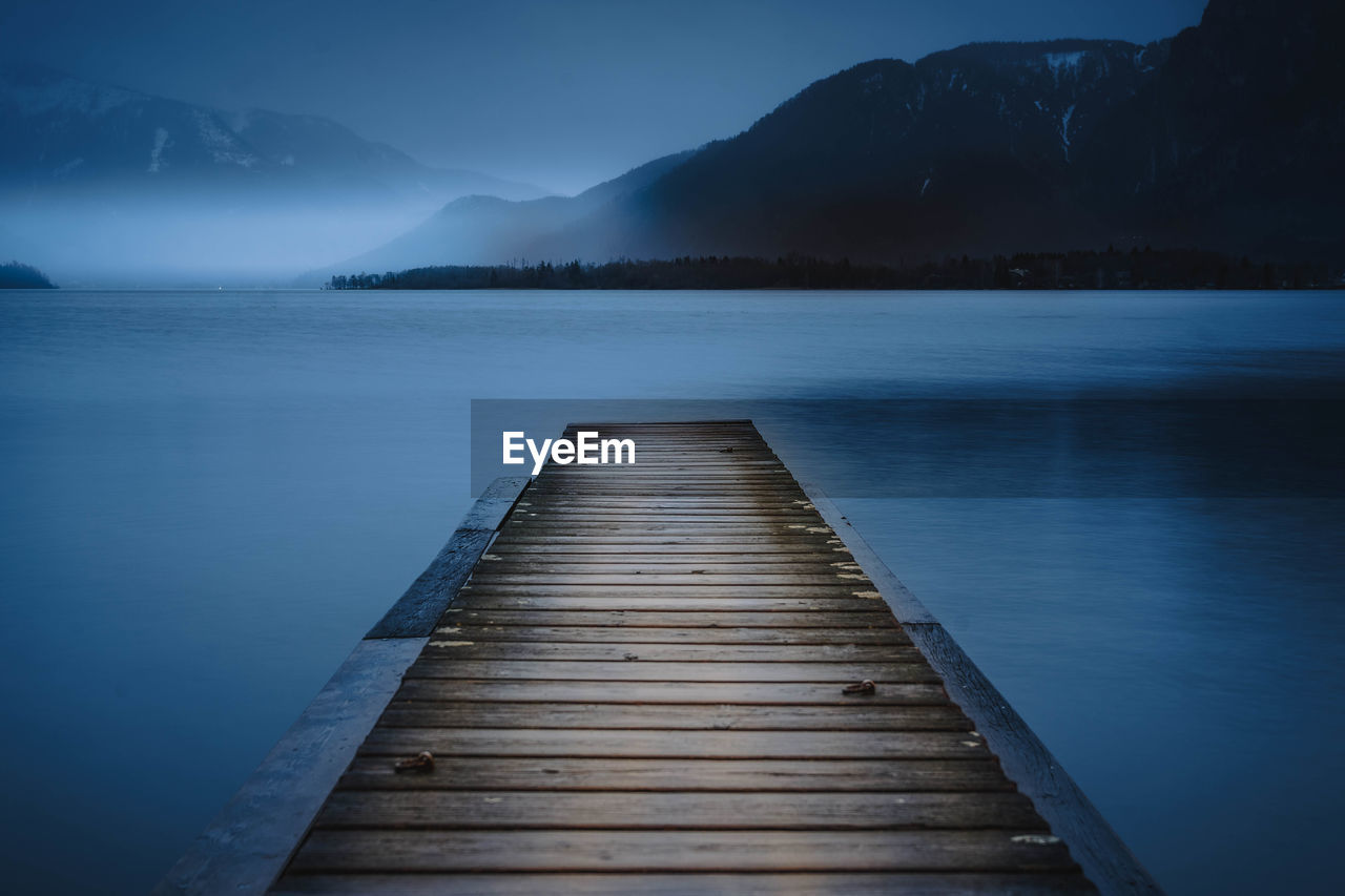 Pier over lake against sky at dusk